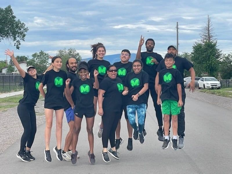 Mini Money students jumping together in team shirts